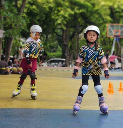 dua orang anak perempuan bermain inline skate di sebuah taman dengan peralatan lengkap