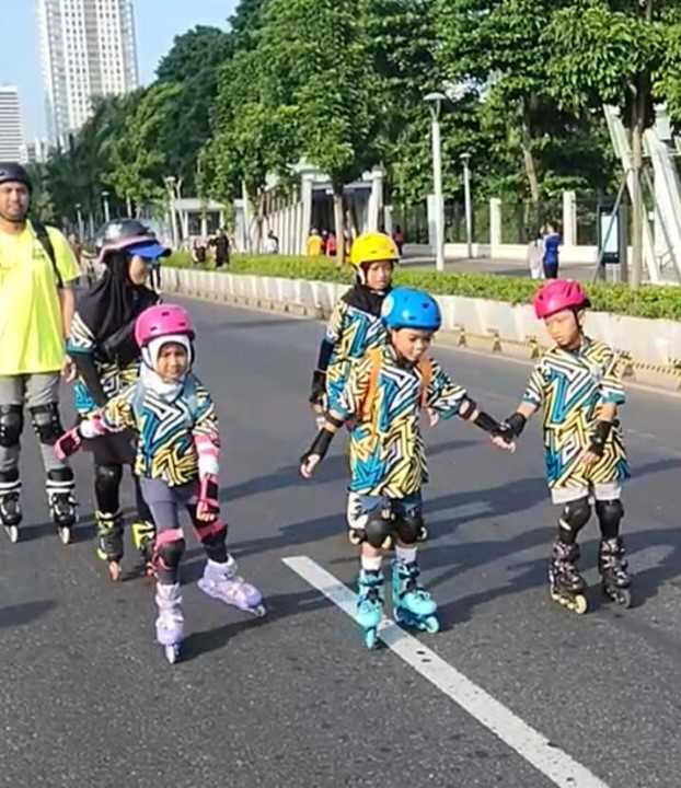 empat orang anak menggunakan sepatu roda di acara car free day didampingi oleh 2 orang dewasa di jalan raya