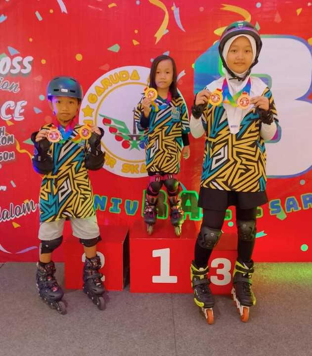 tiga orang anak memamerkan medali saat menggunakan peralatan sepatu roda