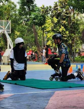 dua orang berlatih cara berdiri menggunakan sepatu roda dengan alas matras